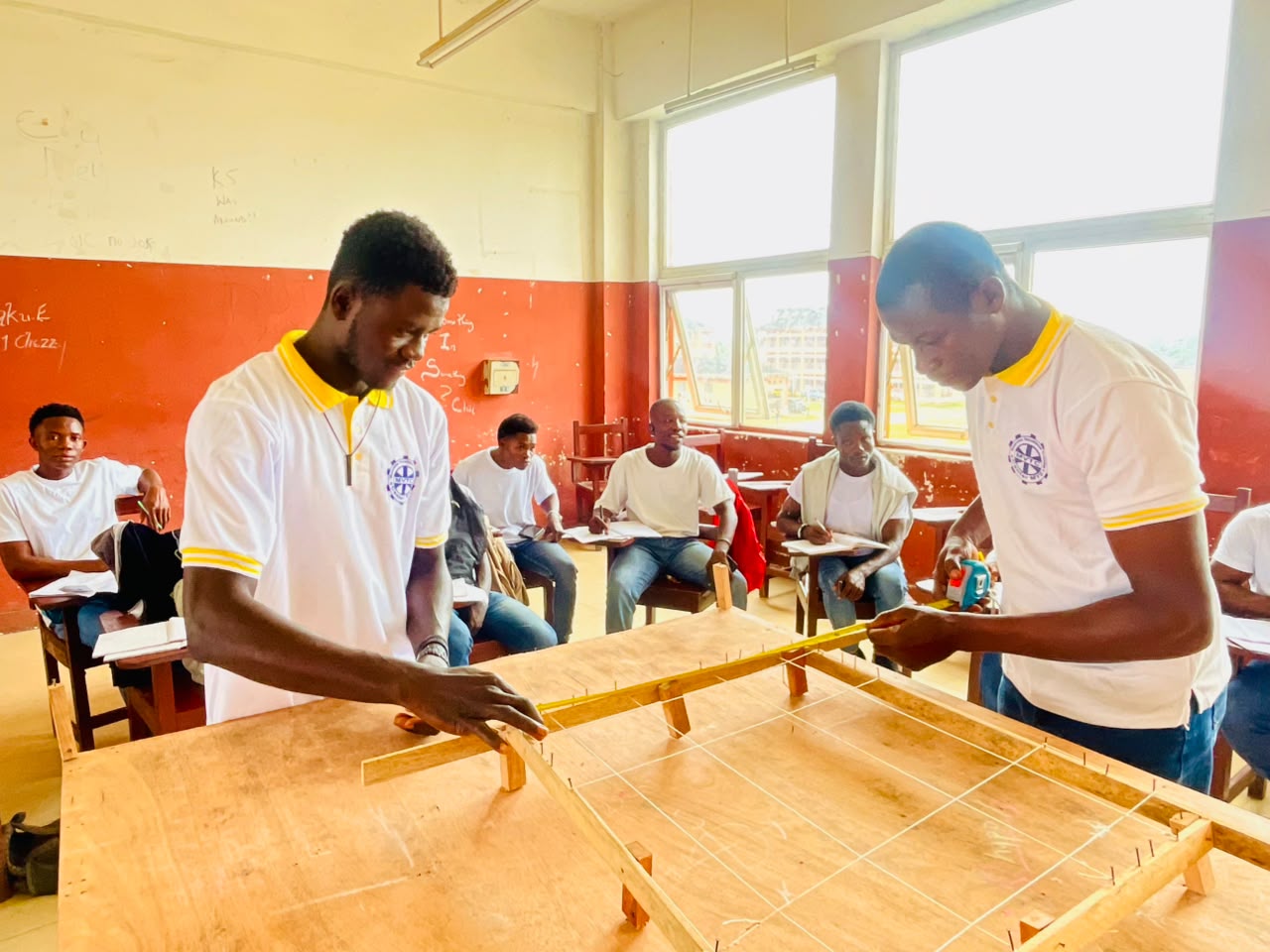 Students measuring a formwork frame during a building trade practical session